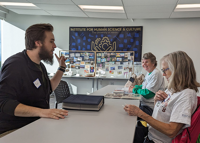 People chatting over a binder of postcards